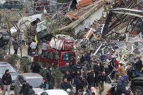 People gather as cars drive past rubble in Beirut after a ceasefire between Israel and Hezbollah took effect on Nov 27.