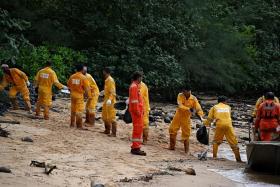 When the tide comes in at East Park, the workers form a human chain to load the boat with bags of oil-stained sand, which brings it back to a staging area. 