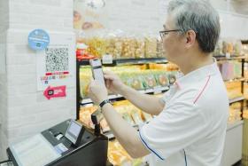 Deputy Prime Minister Gan Kim Yong demonstrates making a purchase at a bakery using PayLah. 