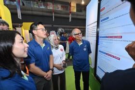 Minister for Social and Family Development Masagos Zulkifli (right) looking at a demonstration of the TampinesCaresGoWhere website on Aug 17.