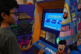 Chiong Tze Yu, 13, answering a question about online shopping scams on a "children's ATM" featuring an interactive game. 