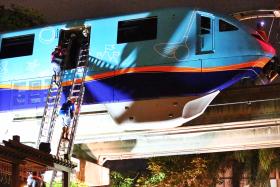 Two of the trapped passengers climb down from the stranded monorail train. 