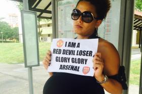 ONE FM 91.3 deejay Cheryl Miles at a bus stop in Bishan while fulfilling her end of a dare after Manchester United lost to Arsenal.