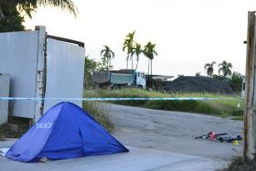 The dead body of the cyclist covered by a blue police tent. He was killed in an accident involving a tipper truck at the entrance of a construction site.