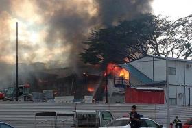 DESTROYED: Workers watch as firefighters battled the blaze (above), which completely gutted the second and third storeys of the workers&#039; dormitory.