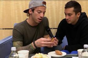 Josh Dun (left) and Tyler Joseph from Twenty One Pilots examine a curry puff.