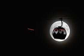 The moon rises behind a car on the The Emirates Air Line (cable car) in London&#039;s Docklands on November 13, 2016