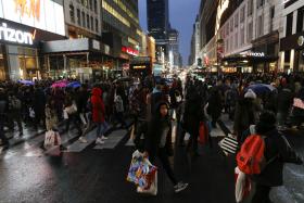 Shoppers cross the street carrying retail bags during Black Friday events 