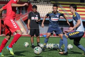 Albirex Niigata coach Kazuaki Yoshinaga (second from left) oversees a training session.