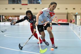 Singapore women&#039;s floorball captain Amanda Yeap (right) fending off the challenge of Indonesia&#039;s Rahmadani Eka Anjar in the group stage. 