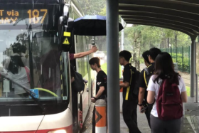 A bus driver sheltering students from ITE College West during heavy rain.