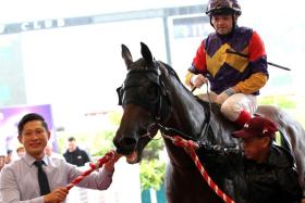 A smiling Jason Ong sheltering from the rain to bring back to scales the first leg of his June 30 treble, Lucky Goal (Manoel Nunes).
