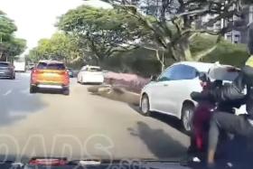 The motorcyclist appears to clip either the car or the barrier, sending him skidding across the road directly into the path of an oncoming orange car.