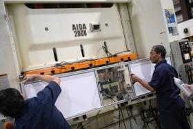 Floor supervisors attaching a sound shield with material which absorbs noise onto a metal stamping machine for bicycle components at Nakano Metal Press on Oct 17.