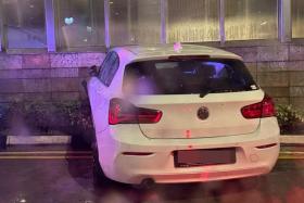 In a photo posted on Facebook, a white BMW car is seen with its front wheels mounted on the kerb in front of a building.