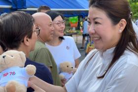 Wah &amp; Hua CEO Melissa Tan (right) giving out the PAP teddy bears at Bedok 85 Market with East Coast GRC MP Cheryl Chan (background, in white) on Nov 17.