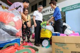 DPM Gan Kim Yong (centre) and South West District Mayor Low Yen Ling (right) helping Madam Chee Wot Yeen (in yellow) weigh the old clothes and newspapers that she brought to Keat Hong CC.