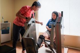 ActiveSG Instructor Victor Ng, 51, helps stroke survivor Maya Seah, 44, as she works on strengthening her legs at the Enabling Village ActiveSG Gym on Dec 19.