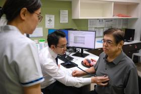 Associate Professor Kenneth Chew (centre), with senior staff nurse Ivy Tan, checking on patient Lam Theam Fatt, who is part of the Heartlanders initiative.