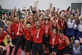 Marsiling Secondary School's Nick Daniel Maliqi Abdullah holding the trophy aloft as his team and supporters celebrate their win on Aug 12.